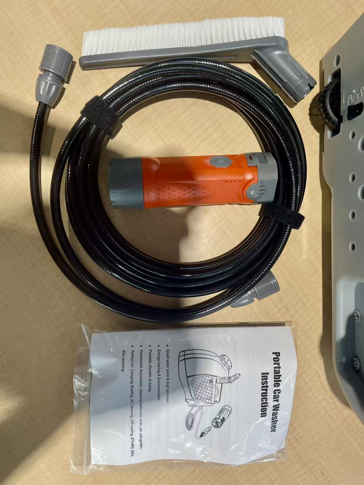 12V portable orange pressure washer cleaning an outdoor air conditioner unit with 15L water tank and adjustable spray gun